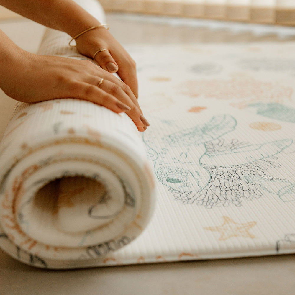 personne en train d'enrouler le tapis de jeu xl le coquillage